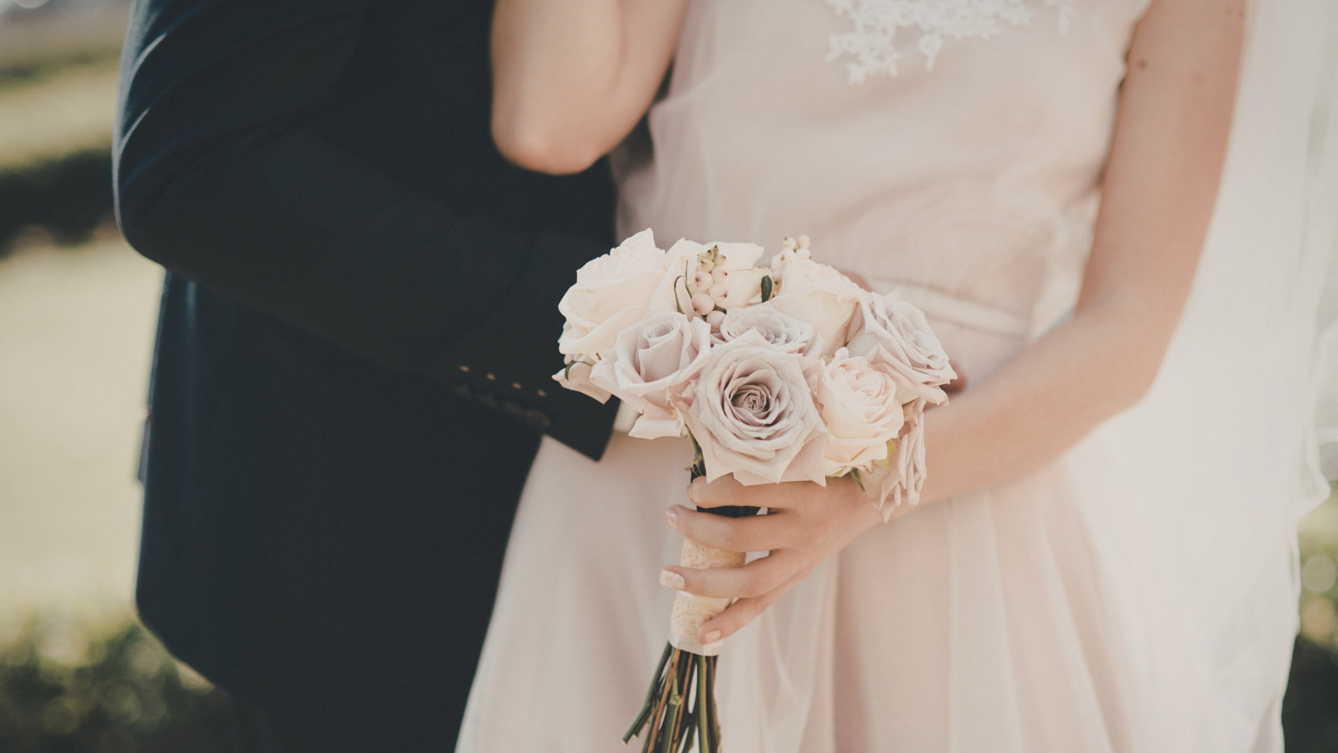 A couple holding a wedding bouquet in formal attire