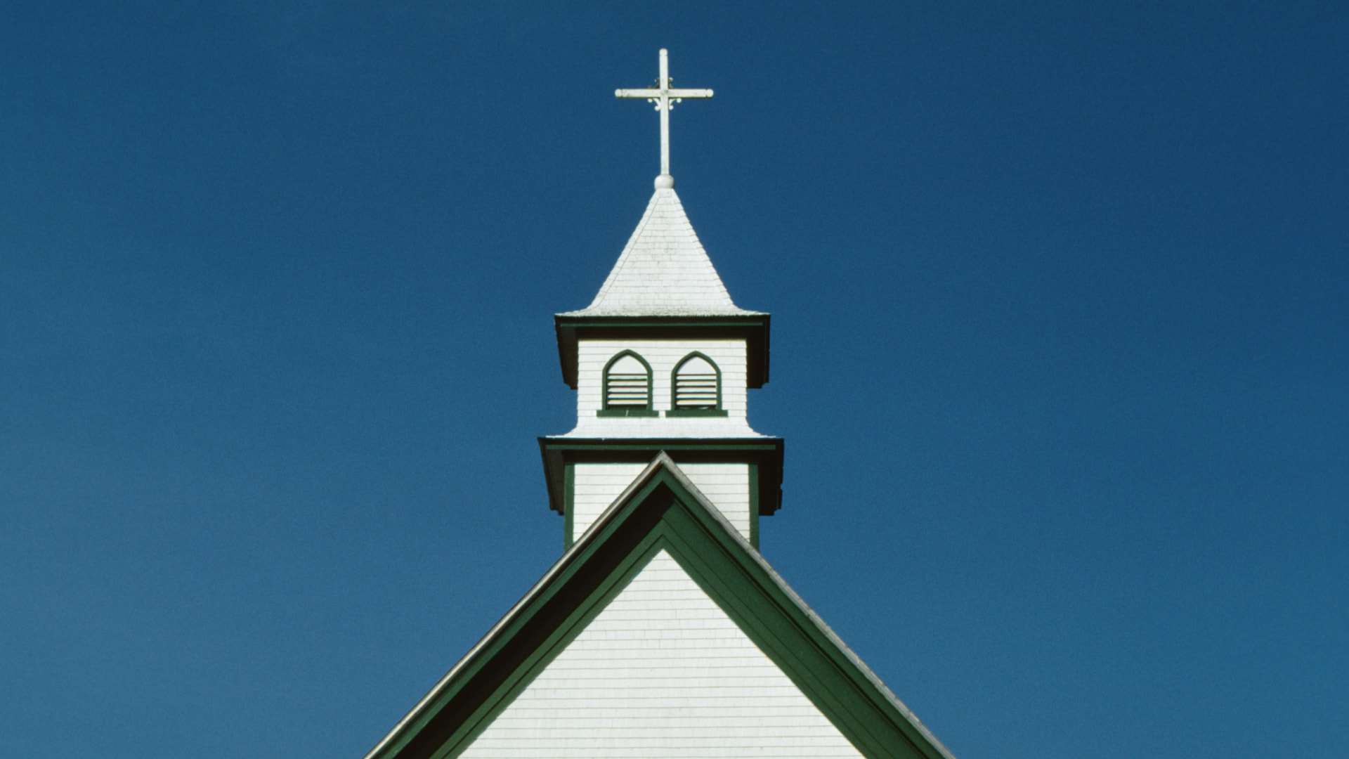A white church steeple against a blue sky